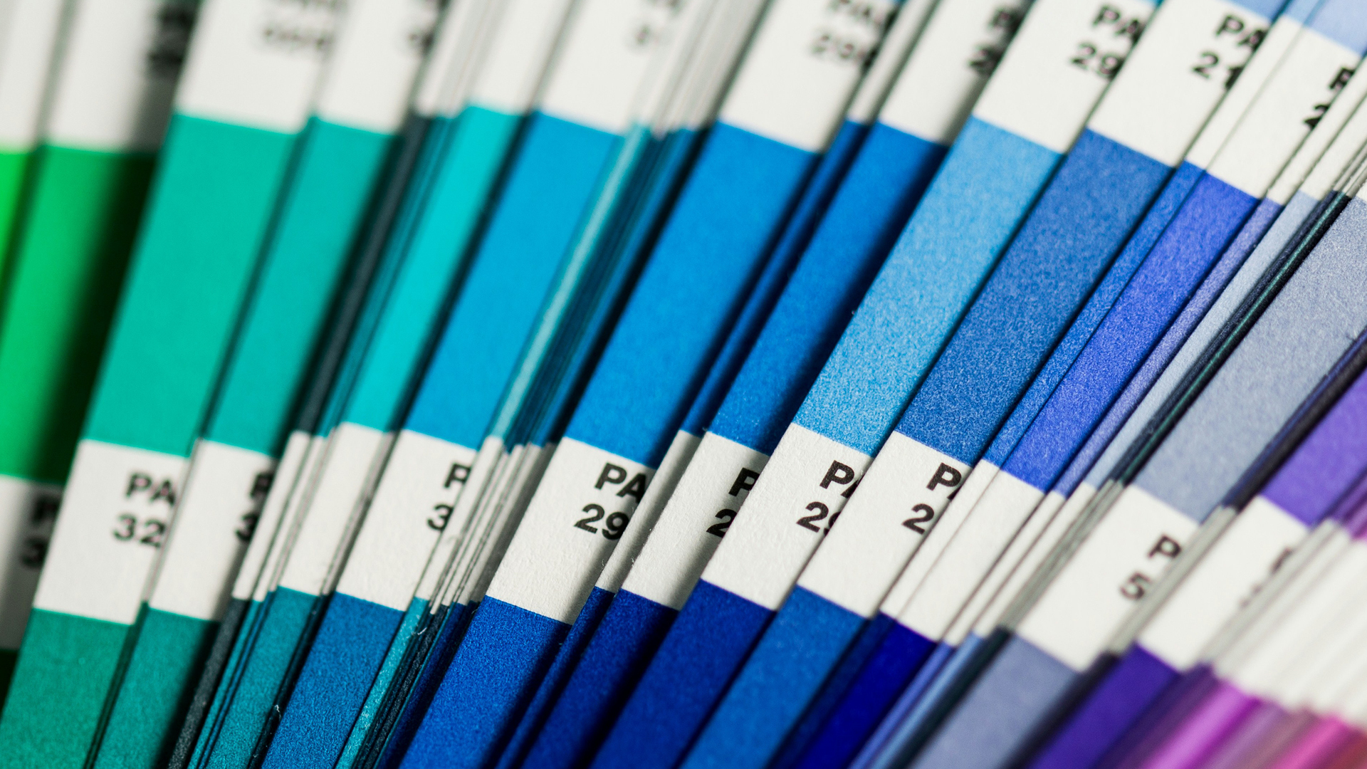 Pantone colour swatches fanned out in a gradient from green and teal through blues to purple.