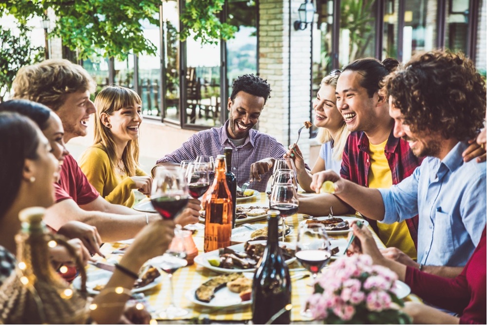 Guests enjoying a lively group dinner on an outdoor restaurant terrace.