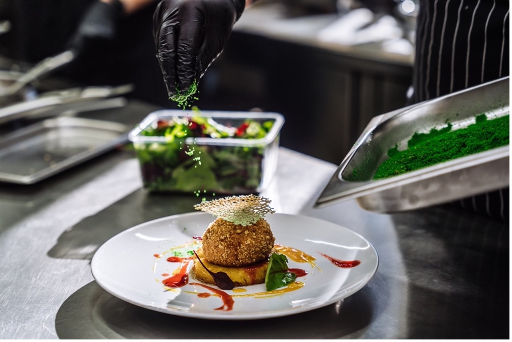 Chef plating a gourmet appetizer in a hotel restaurant kitchen.